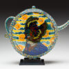 A colorful teapot with a bird on it.