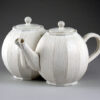 A white teapot and tea pot sitting on top of a table.