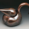 A metal sculpture of a swan sitting on top of a table.