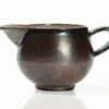 A brown ceramic pitcher with a silver rim.