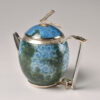 A blue and green tea pot with a handle.