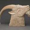 A ram head sculpture is shown in white clay.